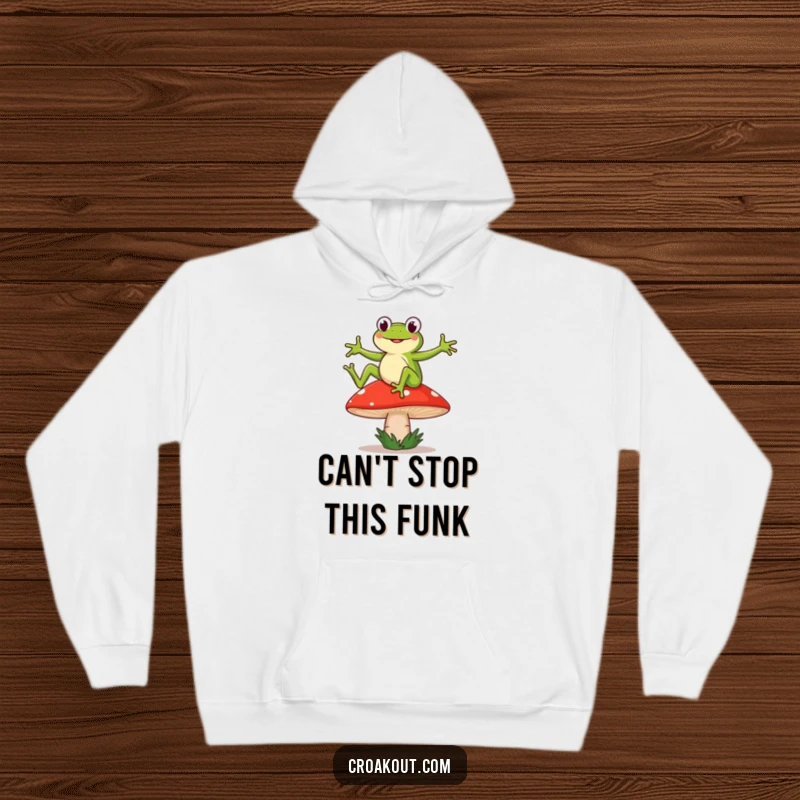 Funny hoodie depicting a frog character doing a silly dance on a wobbly mushroom, exuding whimsical, humorous charm.