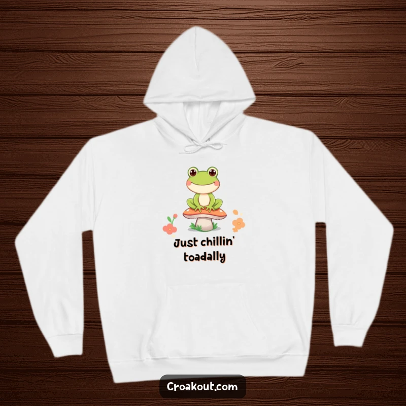 Funny frog hoodie featuring an overjoyed frog character sitting on a mushroom, its wide grin symbolizing ultimate contentment and playful charm.