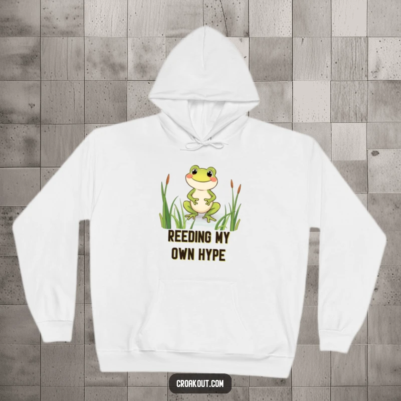 Funny frog hoodie with a beaming character wading through reeds, offering cozy comfort and a cheerful, humorous design.