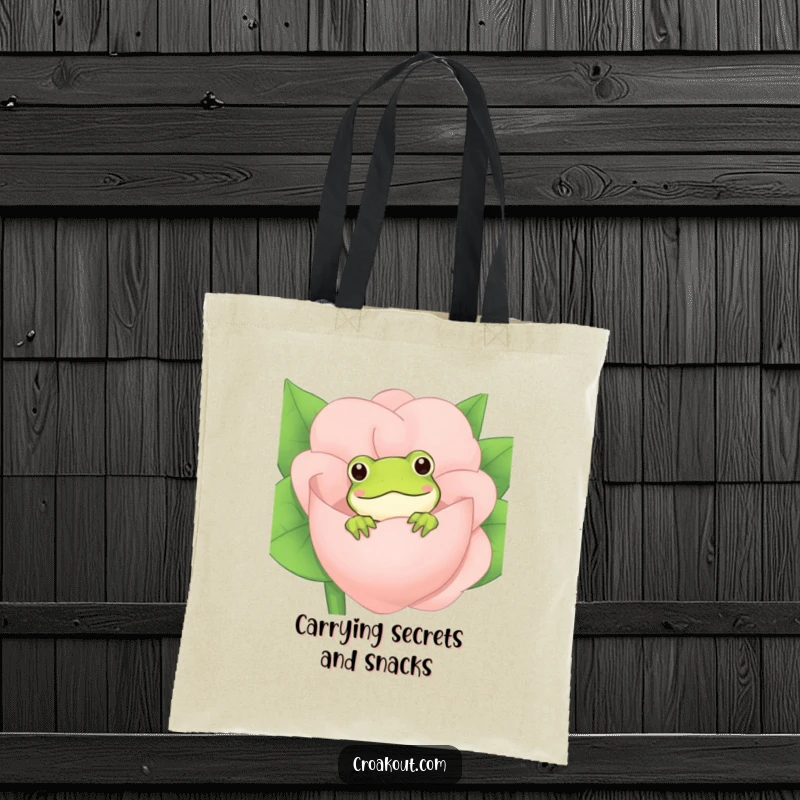Funny Frog Tote Bag: A practical tote featuring a playful frog peeking from behind a blooming flower, ideal for carrying groceries with a smile.